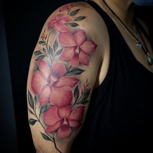 Pink flowers tattoo on the upper arm