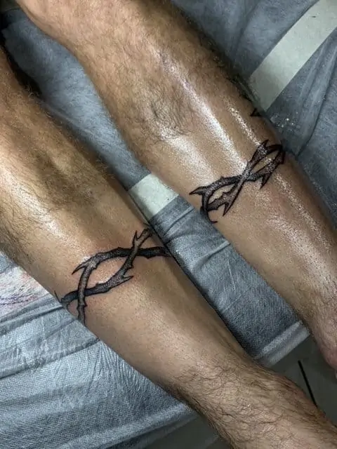 Black and white thorns tattooed around man's legs