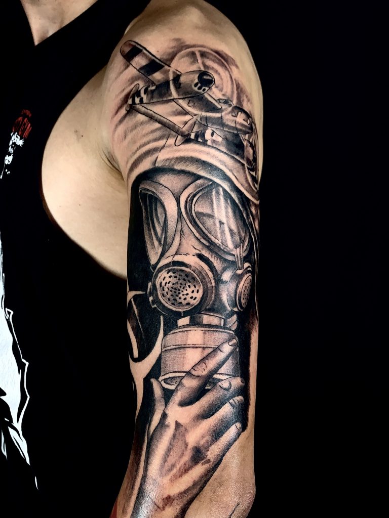 Man with black and white gas mask and plane arm tattoo
