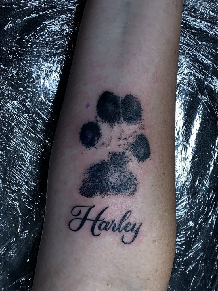 Black dog paw print tattoo on arm