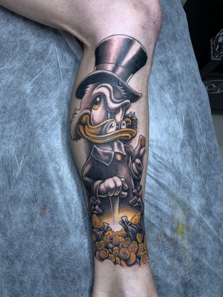 Black and yellow Scrooge McDuck leg tattoo