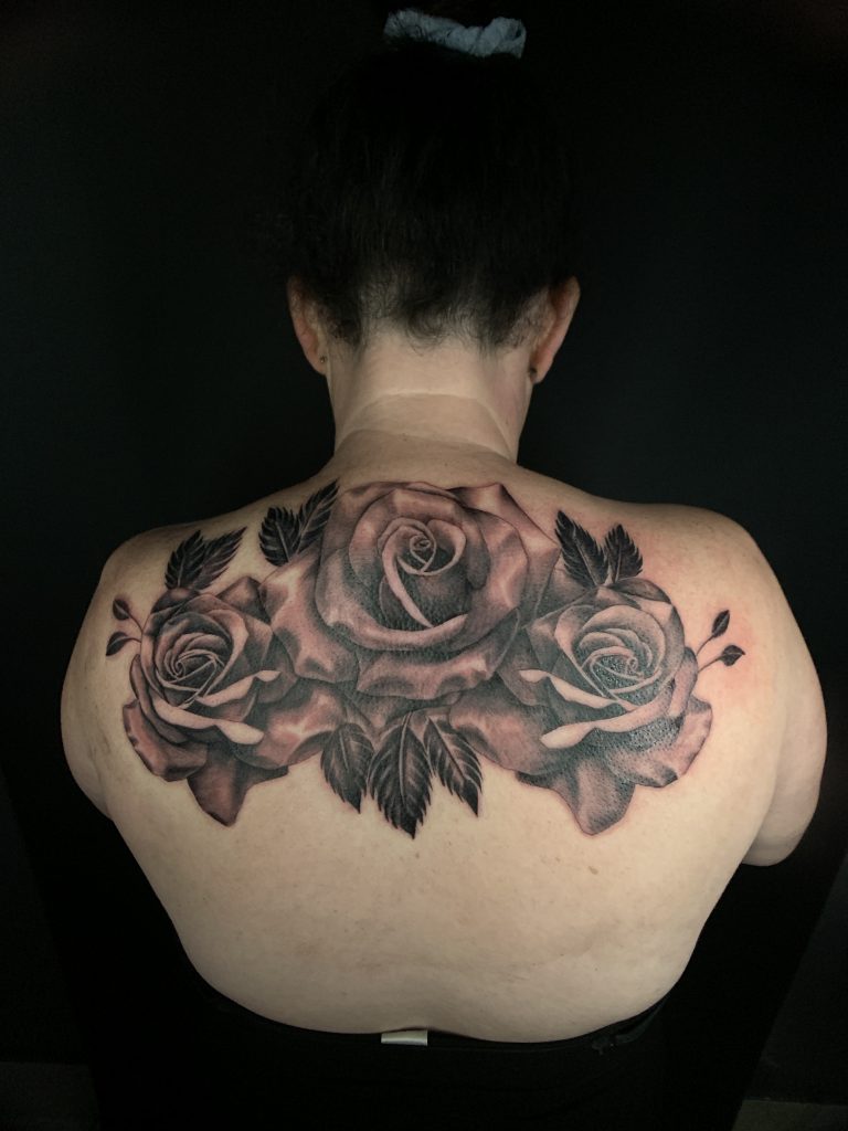 Three black and white roses tattoo on woman's back