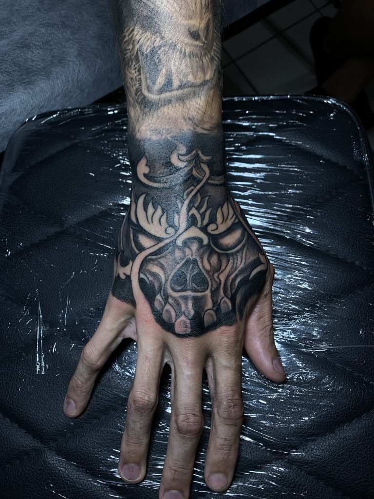 Black and white flaming skull hand tattoo on man