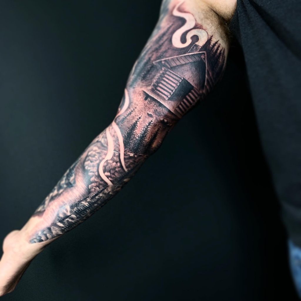 Black and white cabin in the woods tattoo on man's arm
