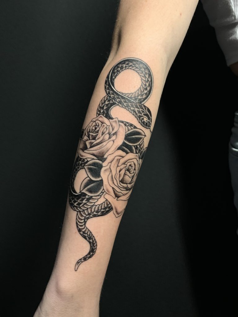 Black and white snake and roses tattoo on arm