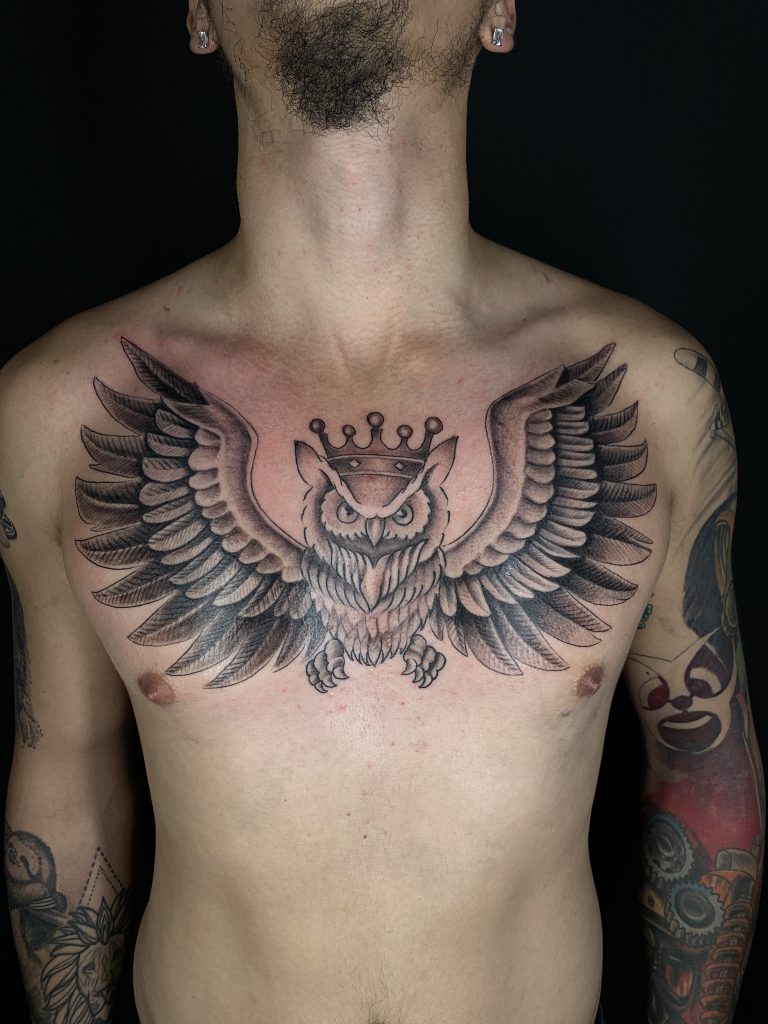 Black and white owl wearing crown chest tattoo on man