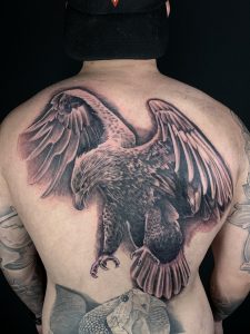 Black and white bald eagle back tattoo on man