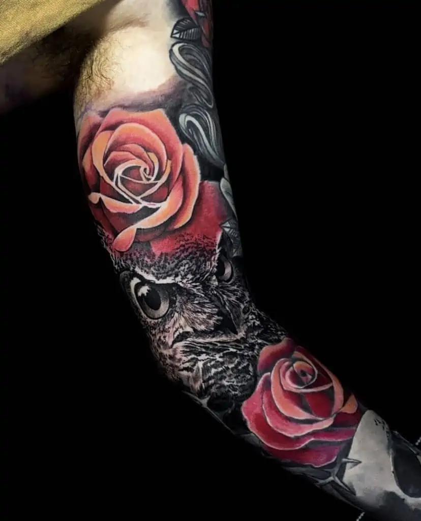 Black and red owl and roses sleeve tattoo on man