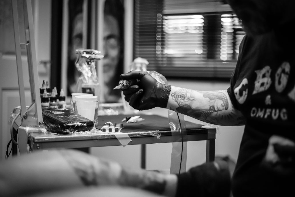 Man tattooing a client in a tattoo parlour